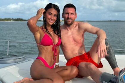 Lionel Messi casually dressed in red shorts, while Antonella Roccuzzo looks glamorous in a pink bikini