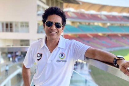 Sachin Tendulkar in a white T-shirt and a sunglass smiling for the camera