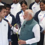 A picture of PM Modi having a friendly chat with Lakshya Sen while posing with the other Olympic players