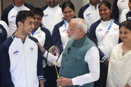 A picture of PM Modi having a friendly chat with Lakshya Sen while posing with the other Olympic players