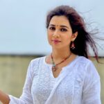 Shreya Ghosal wearing a white salwar suit and posing for the camera