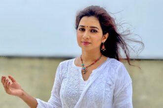 Shreya Ghosal wearing a white salwar suit and posing for the camera